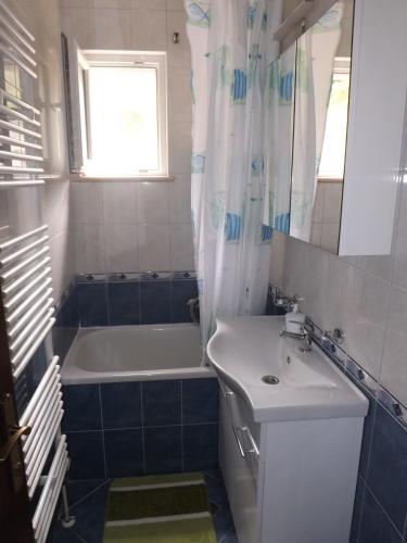 a bathroom with a sink and a tub and a sink and a mirror at Apartman Karmela in Zaton