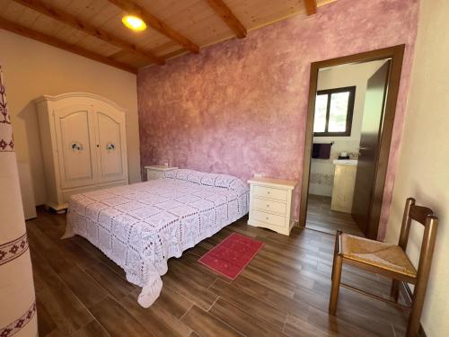 a bedroom with a bed and a chair and a mirror at Agriturismo Piperedda in Irgoli