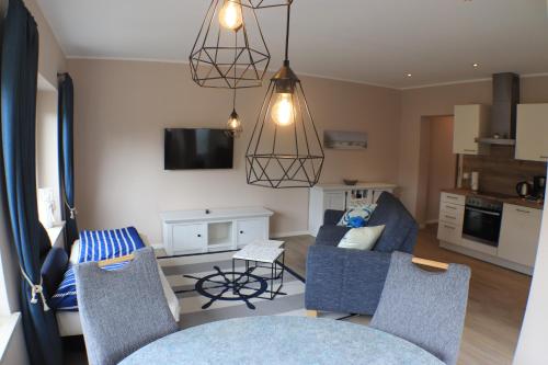 a living room with two blue chairs and a kitchen at Hotel Seeterrassen in Laboe