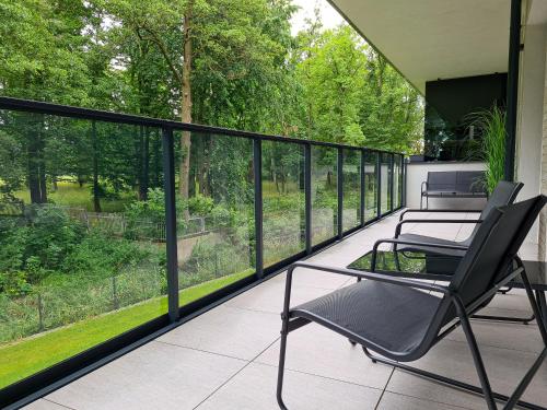 two chairs on a balcony with a view of trees at Nice River Apartment in Ostróda