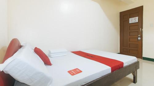 a bedroom with a bed with white sheets and red pillows at RedDoorz @ Western Bicutan Transients Inn in Manila