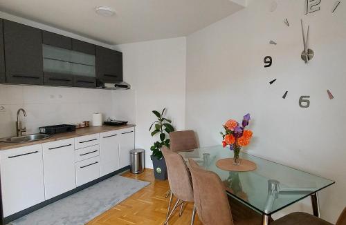 uma cozinha com uma mesa de vidro e algumas cadeiras em Apartman Panorama em Pozarevac