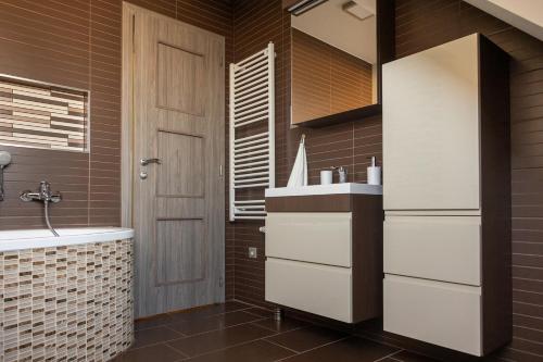 a bathroom with a sink and a white refrigerator at Laza napok apartman - 1 in Veszprém