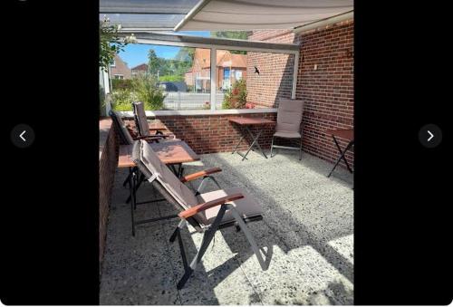 een groep stoelen en tafels op een patio bij Pension Haus Norddeich Mole in Norddeich