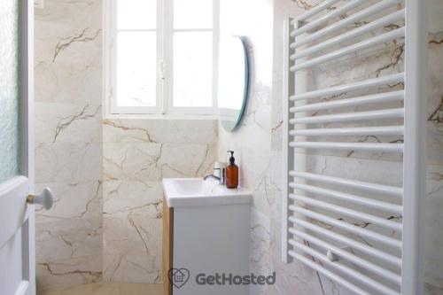 ein Badezimmer mit einem weißen Waschbecken und einem Spiegel in der Unterkunft Charming Flat at the gates of Paris - GetHosted in Asnières-sur-Seine