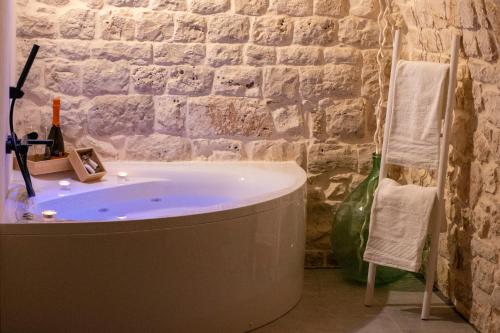 a bathroom with a tub and a stone wall at Suite 20 in Conversano