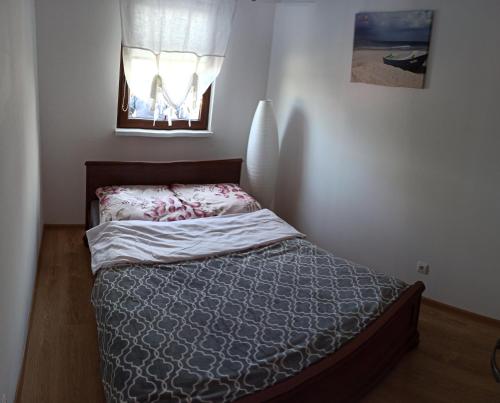 a small bed in a bedroom with a window at Domki Letniskowe Strażnica in Jarosławiec