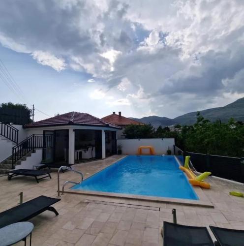 a swimming pool with a patio and a house at Studio apartmani Milović in Trebinje
