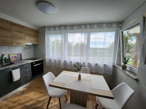 a kitchen with a wooden table and white chairs at Apartma Aleksandra in Sečovlje