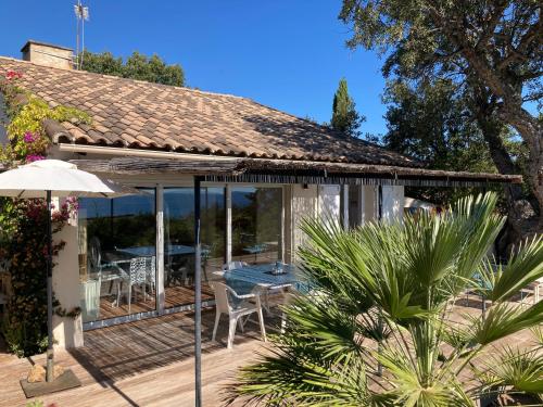 une maison avec une terrasse avec une table et des chaises dans l'établissement VILLA CORSE DU SUD à 200m de la plage, à Zonza