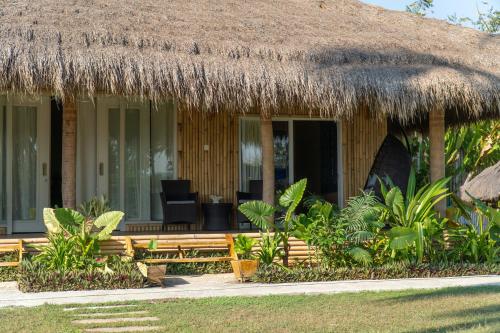 a hut with a thatched roof and a chair in front at Sumba Retreat Kerewe in Waikabubak