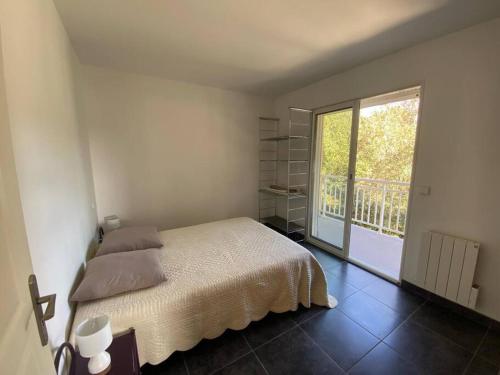 une chambre avec un lit et une grande fenêtre dans l'établissement Appartement T4 - 50m de la mer, à Pietrosella