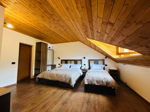 two beds in a bedroom with a wooden ceiling at Bujtina Terthorja in Theth