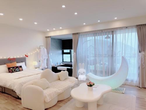 een witte slaapkamer met een groot bed en een bank bij 拾月。頭城無邊際泳池溫泉房 in Toucheng
