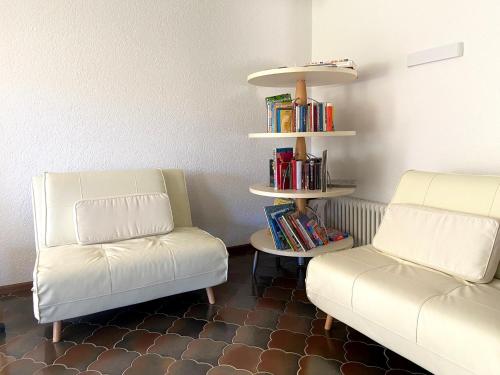 dos sillas blancas y una estantería con libros en Schwarzwaldhaus Sonnenstraße, Oberried-Hofsgrund, Dreisamtal, en Oberried