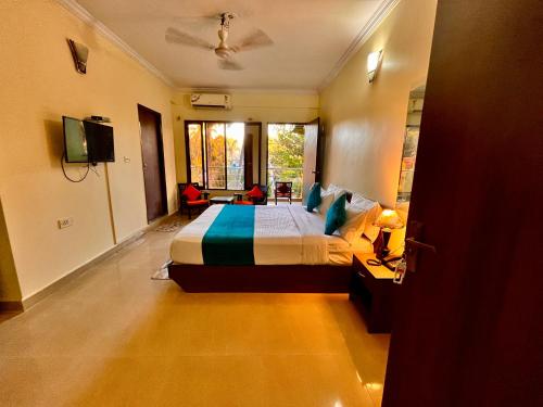 Hamilton Hotel & Resort Goa في Goa: غرفة نوم فيها سرير وتلفزيون
