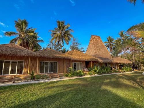 une maison avec un toit de paille et des palmiers dans l'établissement Sumba Retreat Kerewe, à Waikabubak