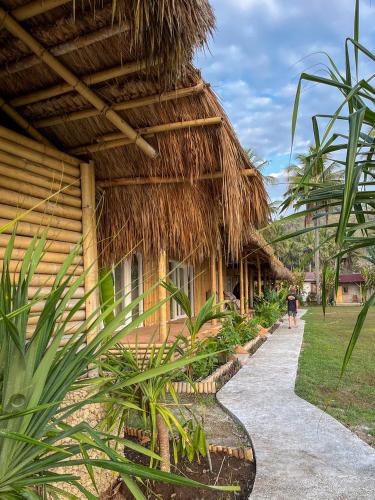 a person walking down a path next to a hut at Sumba Retreat Kerewe in Waikabubak