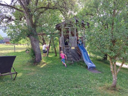 ein Kind, das auf einer Rutsche auf einem Spielplatz spielt in der Unterkunft Fuchsbauernhof in Piding