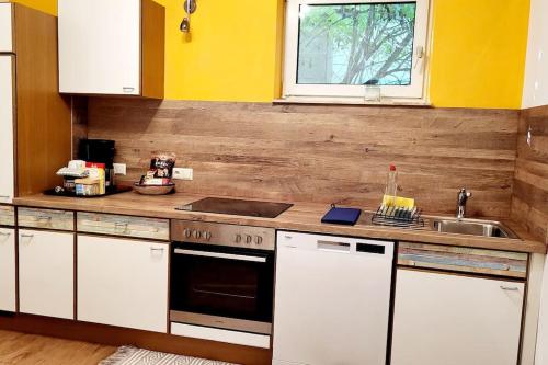 a kitchen with white cabinets and a sink and a stove at Colourful 2.5 Bedroom With Large Balcony & Garden. in Prinzersdorf