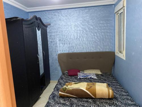 a bed in a room with a blue wall at Jolie appartement oulfa azhar in Casablanca