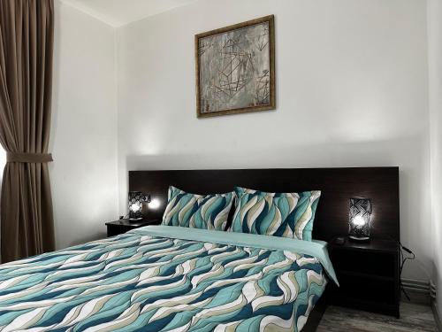 um quarto com uma cama com um edredão azul em Comfort Apartment em Târgovişte