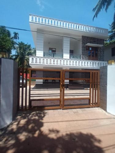 a house with a wooden gate in front of it at Whitehouse Homestay-Iqra Hospital Calicut in Kozhikode