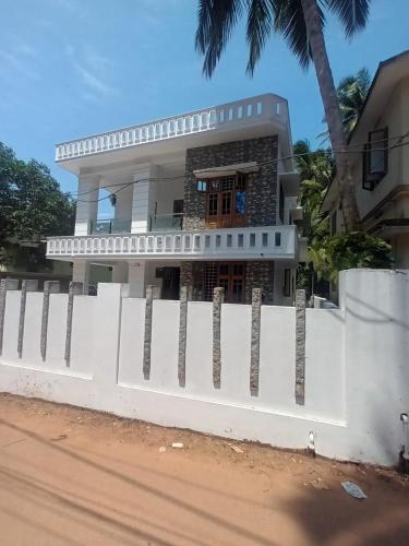 a white fence in front of a house at Whitehouse Homestay-Iqra Hospital Calicut in Kozhikode