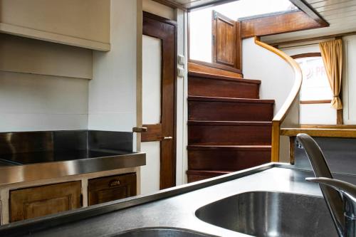 a kitchen with a sink and a stair case at Uniek verblijf op slaapschip (tot 20 personen) nabij het centrum van Leeuwarden in Leeuwarden