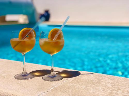 two wine glasses sitting on a table next to a pool at Casal dos Frades in Fontainhas