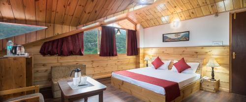 ein Schlafzimmer mit einem Bett und einem Tisch in einem Zimmer in der Unterkunft Hotel Kullu Valley in Kulu