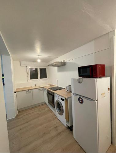 une petite cuisine avec un réfrigérateur et un micro-ondes dans l'établissement Appartement en soubassement, à Port-de-Bouc