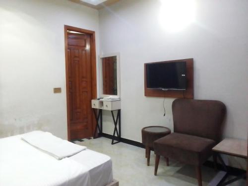 um quarto com uma cama, uma cadeira e uma televisão em Dove Inn Family Residency Johar Town em Lahore