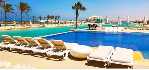 un gruppo di sedie a sdraio accanto alla piscina di Hacienda Bay Chalet Sidi Abdelrahman North Coast a El Alamein