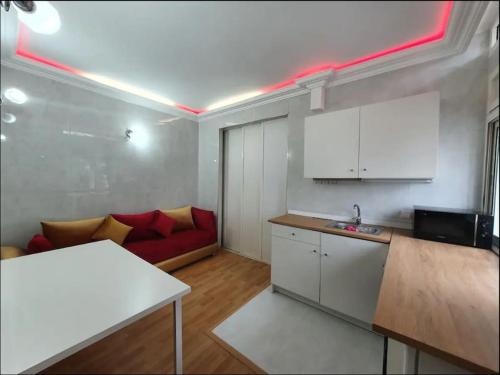 Studio Cosy moderne et climatisé في الرباط: غرفة معيشة مع أريكة حمراء ومطبخ