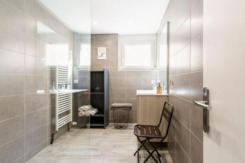 a bathroom with a chair and a walk in shower at Le Gîte de Sandra in Ribeauvillé