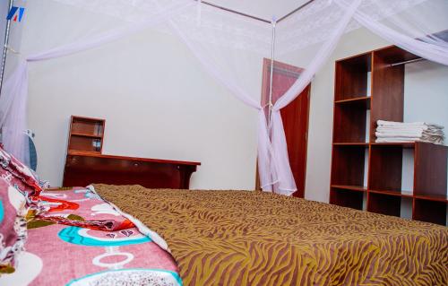 Sunshine Residence في بوجومبورا: غرفة نوم بسرير مع مظلة
