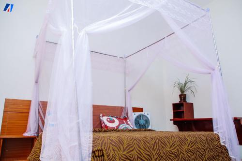1 dormitorio con 1 cama con dosel en Sunshine Residence, en Buyumbura
