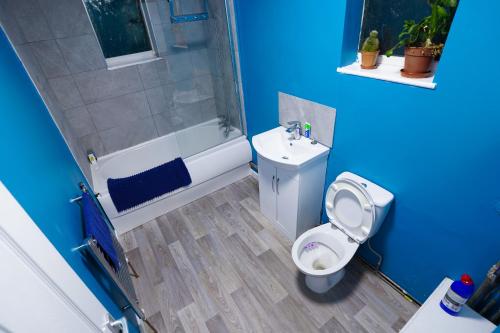 uma casa de banho azul com um WC e um chuveiro em 3 Bedroom home by Ipswich docks. em Ipswich