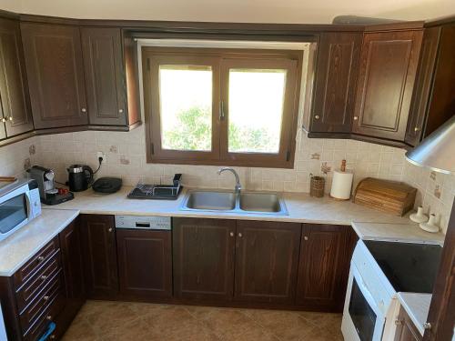 a kitchen with wooden cabinets and a sink and a window at KARMA House by the River in Paramythia