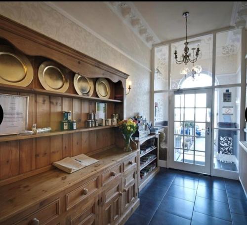 una cocina con armarios de madera y platos en la pared en Promenâd Bed & Breakfast, en Llandudno