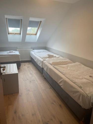 two beds in a room with two windows at HOTEL ZELENÝ DVOR in Senec