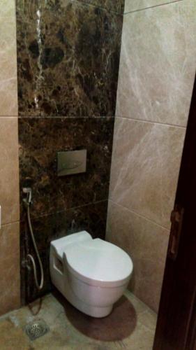 a bathroom with a toilet in a tiled wall at Luxury Flat in Faridabad