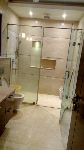 a bathroom with a glass shower and a toilet at Luxury Flat in Faridabad