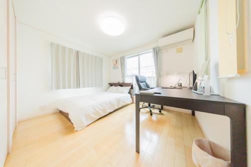a bedroom with a bed and a desk with a computer at Tokyo Private House 大塚の宿 in Tokyo