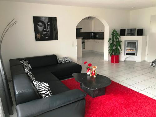 a living room with a black couch and a red rug at Residenza San Remy in Unterkulm