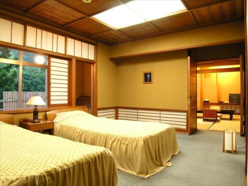 a hotel room with two beds and a balcony at Yunokaze HAZU in Shinshiro