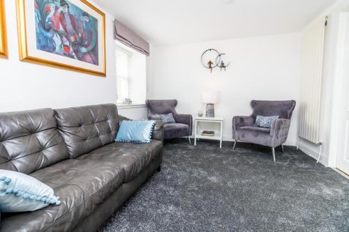 a living room with a brown couch and two chairs at Seaview Cottage Central Dundee in Dundee