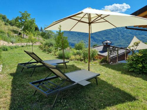 two lounge chairs and an umbrella in the grass at ARPA DI PIETRA - Luxury B&B SPA BIO - Adults Only in Mori