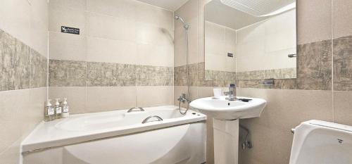 ein Badezimmer mit einem Waschbecken, einer Badewanne und einem WC in der Unterkunft Hansan Hotel in Tongyeong